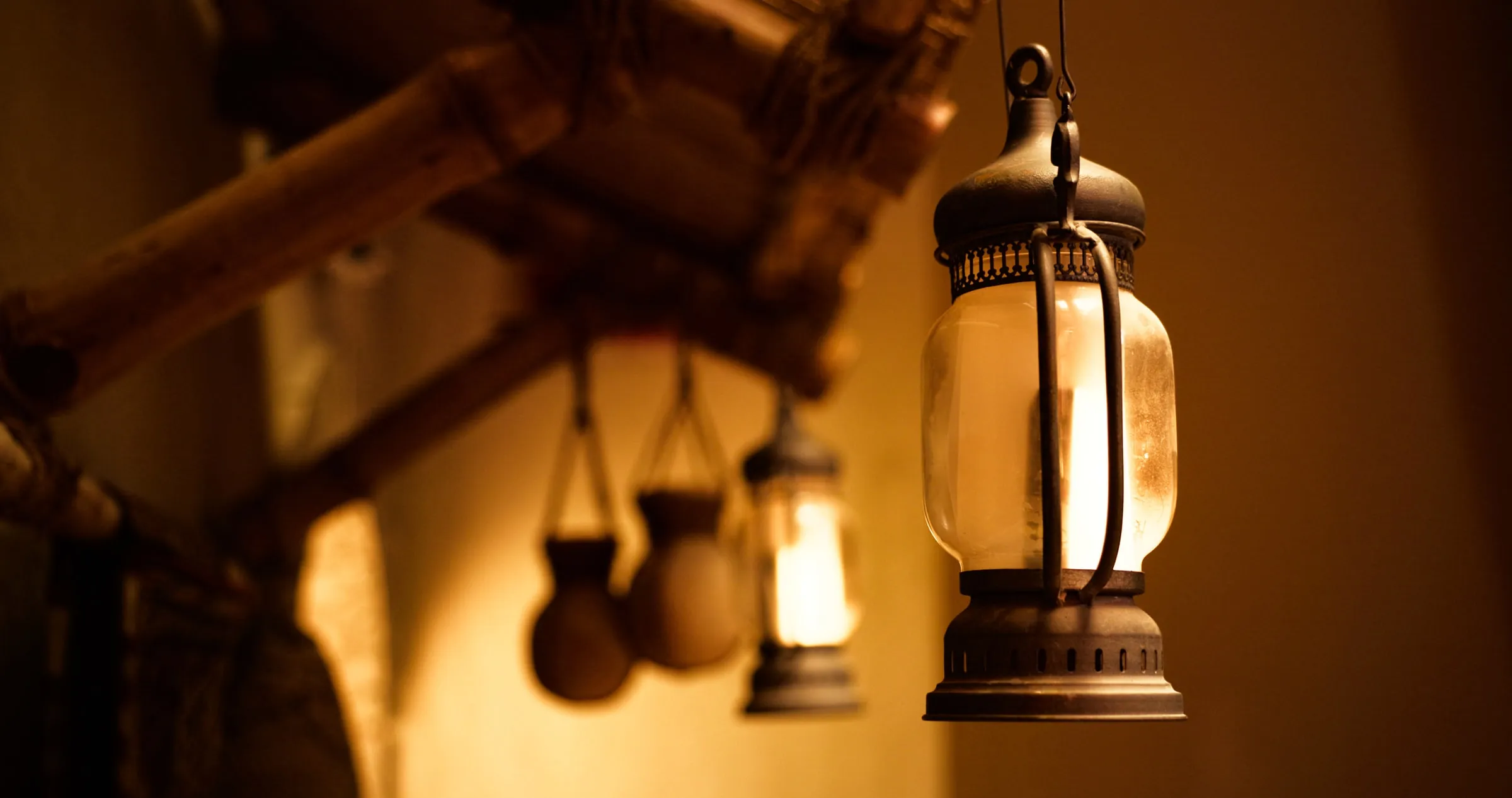 Lit metal lanterns hanging from a timber beam in a heritage interior