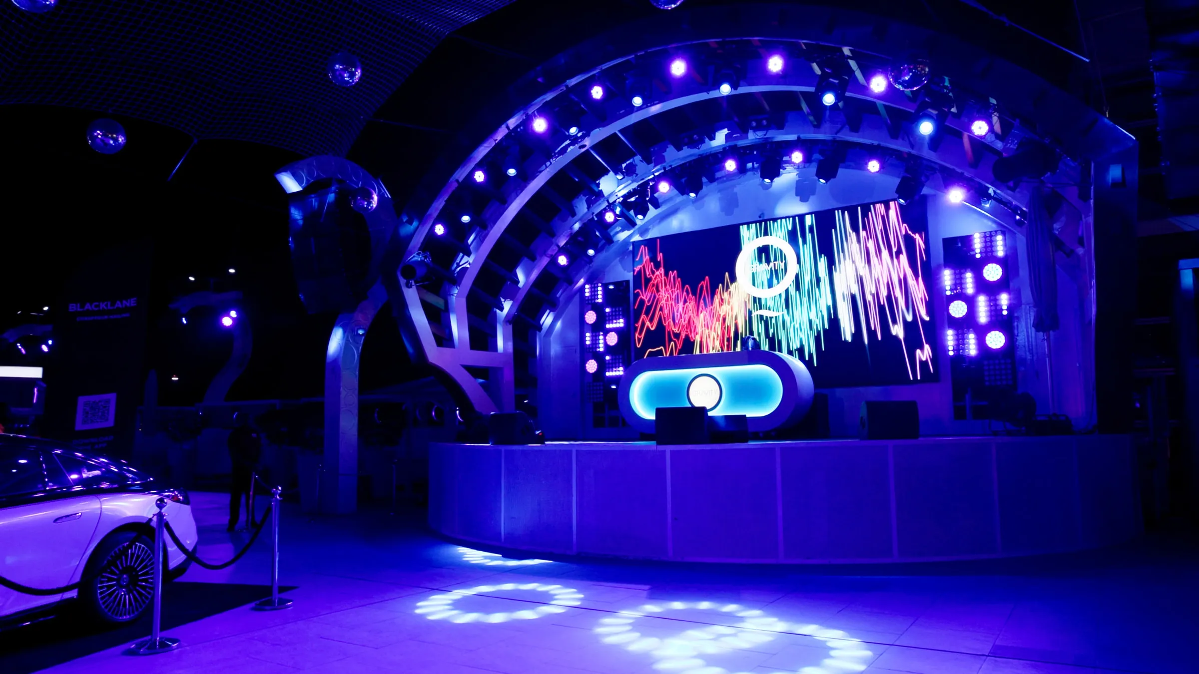 An arched arena stage lit in blue with a full-width LED screen behind the podium